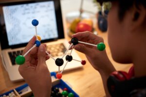 Una buona formazione professionale in materie  stem assicura certamente un ingresso molto facile nel mondo del lavoro, cavalcando tutte le le nuove professioni digitali. Nella foto, un ragazzo studia materie scientifiche, formandosi per mezzo di un modello molecolare.