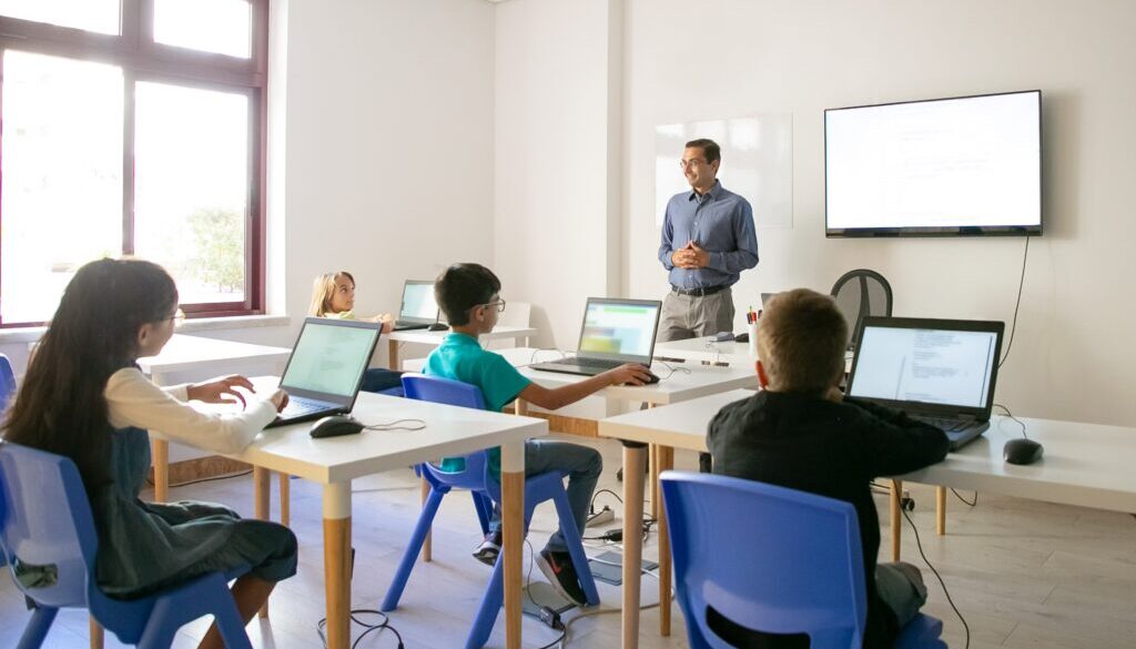 Nel piano di investimenti del PNRR previsti per l'istruzione, viene data grande importanza alla realizzazione di ambienti di apprendimento ibridi per formare i ragazzi alle professioni del futuro. Nella foto, un insegnante che tiene lezione in un'aula scolastica provvista di strumenti tecnologici.