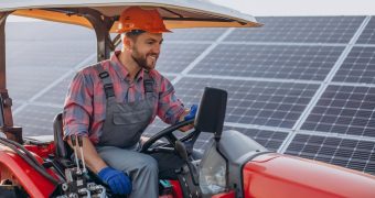 Mekhan offre diversi corsi per formarsi come tecnici di veicoli agricoli e commerciali, basati tutti sul modello learning by doing. Nella foto, un uomo che guida un veicolo agricolo, con pannelli solari sullo sfondo.