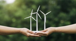 Per la costruzione di un impianto eolico sono richieste anche grandi doti progettuali e di coordinamento del personale. Nella foto, due mani che tengono simbolicamente il progetto di un parco di turbine eoliche.